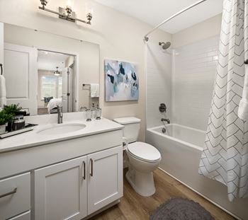 a bathroom with white cabinets and a white tub and shower